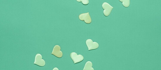 Green hearts on a green pastel background. Valentine's Day. Top view, flat lay, copy space. Banner
