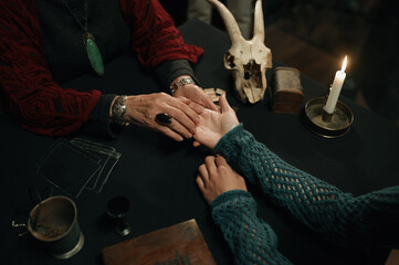 Top view fortune teller and client hands over table with spiritual attributes