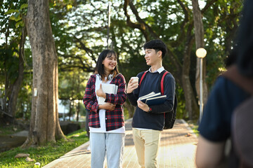 Shot of two asian student talking to each other while going to lecture at the university