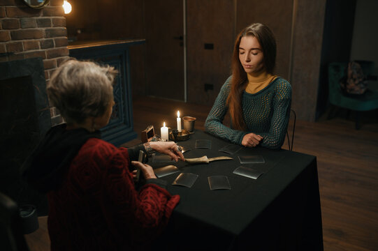 Young woman asking advice at mature old gypsy taro reader