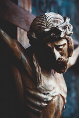 Jesus Christ crucified. Closeup fragment of an ancient wooden statue. Image with deep shadows.
