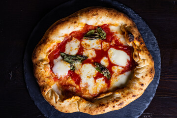 Pizza Margherita napoletana gourmet con sugo di pomodoro, mozzarella e basilico fresco servita in una pizzeria