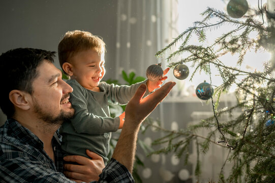Happy father and son decorating Christmas tree at home - Powered by Adobe