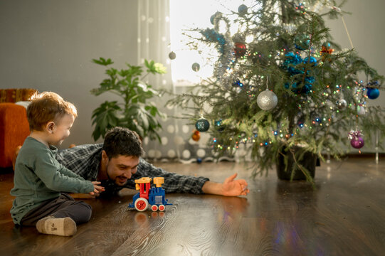 Happy father and son playing with toy train at home
