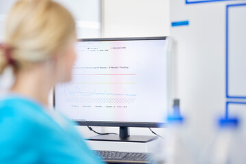 Female scientist and test results on computer screen in a lab