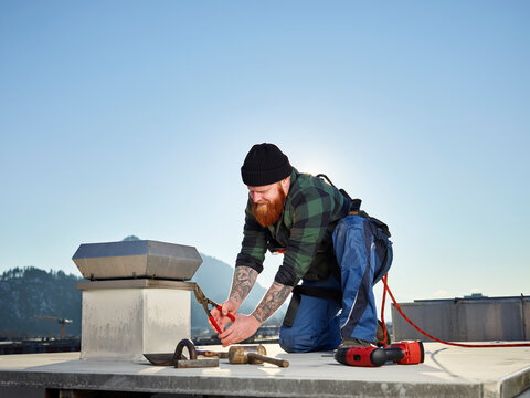 Roofer working with pliers on sunny day