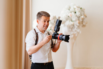 A male photographer in a white shirt with a camera on a leather belt unloading. 