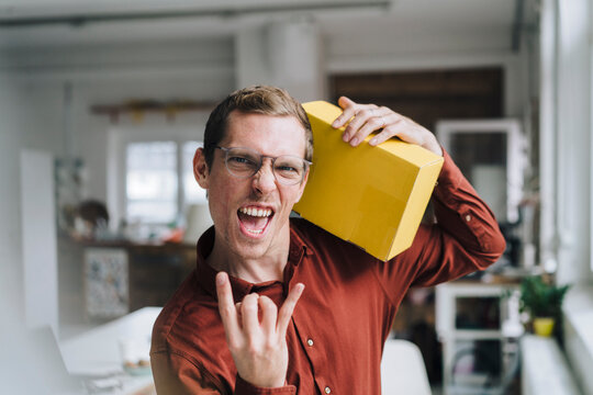 Cheerful businessman gesturing and standing with box in office