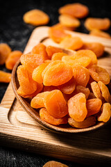 Dried apricots in a plate on a cutting board. 