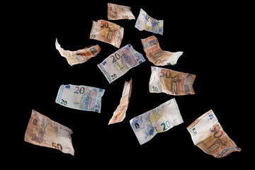 Flying money, twenty and fifty paper banknotes in euro currency coming down, isolated on a back...