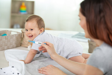 mother measures the temperature of a baby child kid