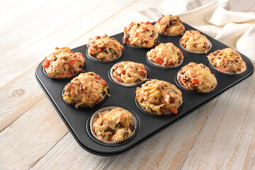 Pizza muffins in a baking tray fresh from the oven, made from yeast dough with vegetables, sausage...