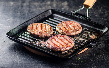 Cooking a delicious grilled burger on a pan with oil bubbles.
