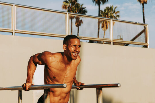 Happy man exercising on parallel bars