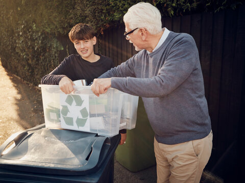 Grandfather and grandson putting separated waste in waste bin