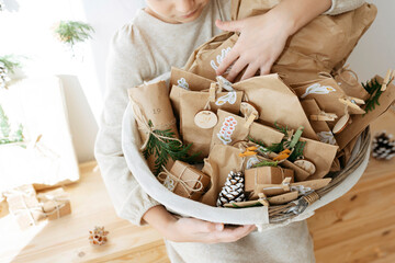 Girl holding basket of advent calendar gifts at home