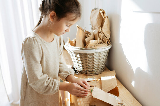 Cute Girl Opening Gifts On Cabinet At Home