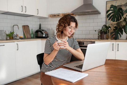 Freelancer Holding Coffee Cup Using Laptop On Table At Home