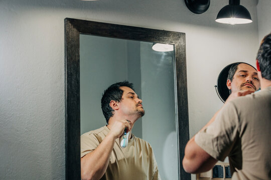 Man with electric razor shaving in bathroom