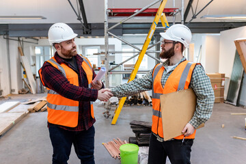 Young engineers shaking hands with each other at construction site