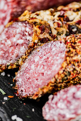 An assortment of delicious salami sausage on a stone board with rosemary. 