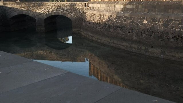 Puente con agua de un foso de una fortaleza al atardecer