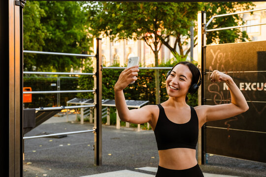 Young asian woman taking selfie on cellphone during workout outdoors
