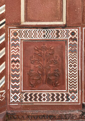 A decorative border and carved floral design on the wall of an ancient building. Details of Mogul art and architecture from Taj Mahal, India.