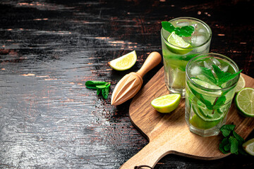 Mojito with pieces of lime on a cutting board.