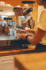 Professional coffee brewing in coffee shop. Barista make coffee cup from coffee machine in warm cozy atmosphere in small cafe.