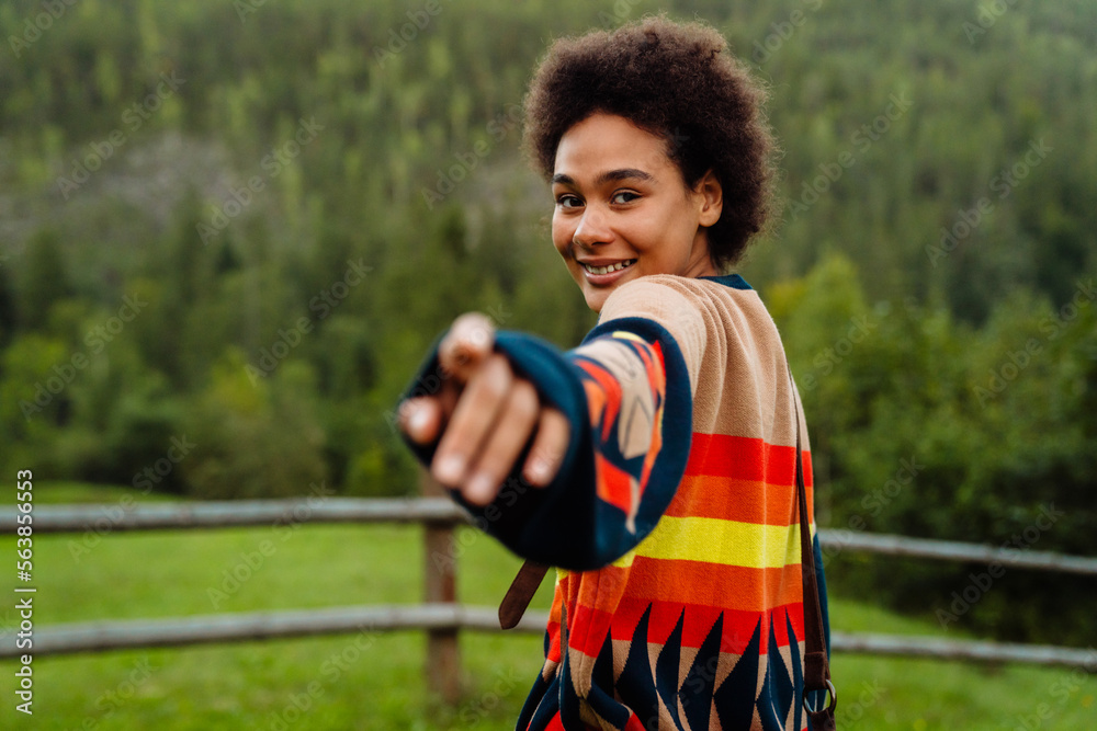 Wall mural young woman reaching her arm forward while walking in green forest