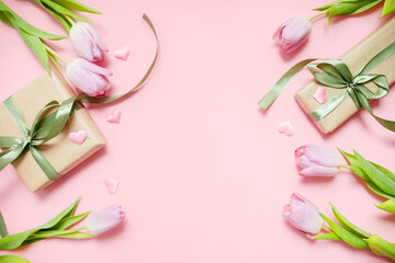 Naklejka na ściany i meble gentle festive layout with tulips, hearts and a gift with green ribbons on a pastel pink background. copy space. top view. flat lay. concept of mother's day, valentines day, eighth of march