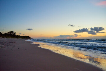 Sea coastline with waves. Baltic sea beach against dramatic cloudy sky at sunset. Panoramic nature landscape