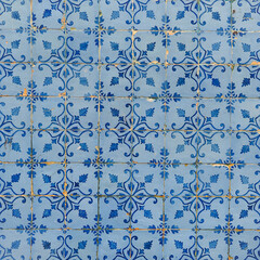 Damaged, faded, not corrected, vintage azulejos, glazed ceramic tiles with blue ornaments on building wall. Heritage Concept of traditional Portuguese art.