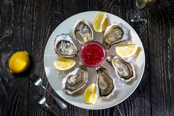 open oysters in a large plate with sauce and lemon
