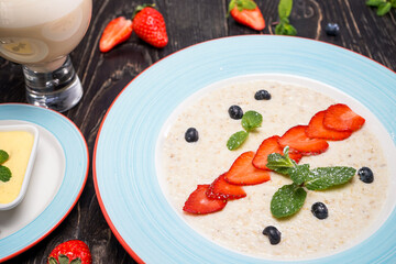breakfast milk porridge with strawberries on a dark background
