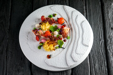 beautiful salad with octopus on a shaped plate on a dark background
