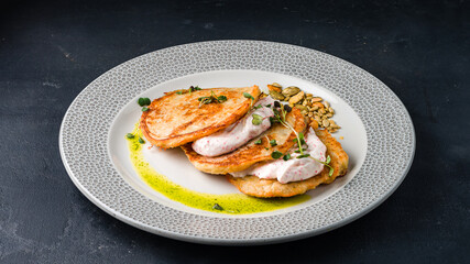 Fried potato pancakes with caviar sauce and pumpkin seeds.
