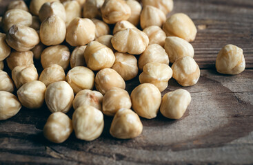 Heap of roasted hazelnuts close-up on a wooden background.