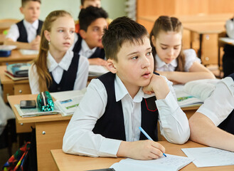 Teenage students are sitting at a desk at school. A boy in a school uniform. The concept of education