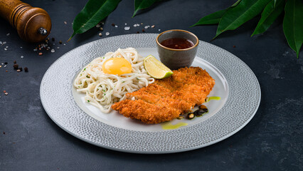 Lunch fried breaded chicken fillet with with pasta, egg and sauce.