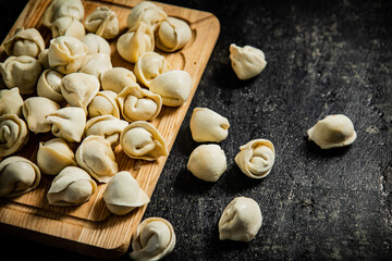 Fototapeta na wymiar Raw homemade dumplings on a wooden cutting board. 