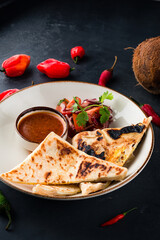 Flatbread stuffed with sauce and fresh vegetable salad on dark background.