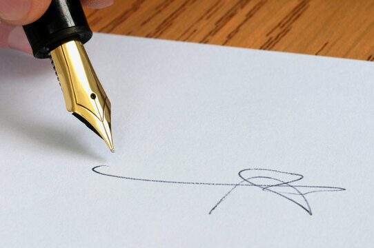 Signature avec un stylo plume en gros plan sur une feuille blanche