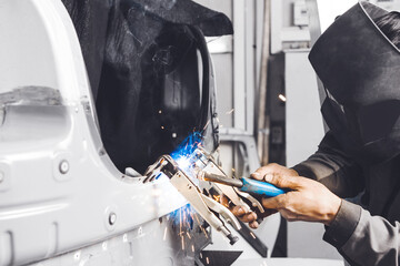 Body shop worker welding car body. Work with carbon dioxide weld.