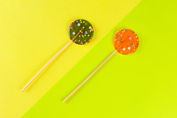Two round lollipops on yellow and green background