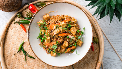 Glass noodles stir fry with chicken, carrots, onions, sweet peppers, green peas and microgreens.