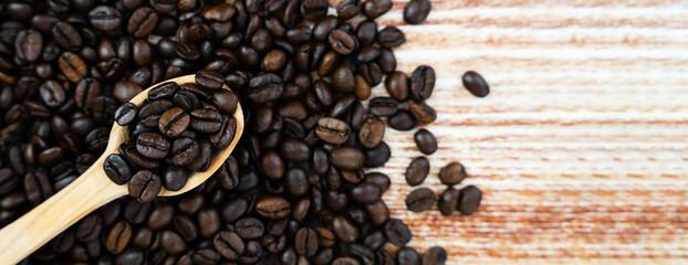 Aromatic natural coffee beans in a spoon on the background of coffee beans. Banner. Top view. Place for text. Selective focus.
