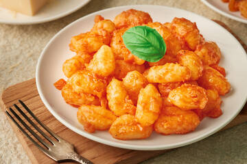 Close-up of a plate of POTATO GNOCCHI in tomato sauce and a fork on a wooden cutting board. High angle view.