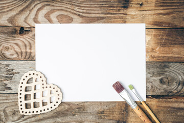 Blank sheet of paper and brushes for drawing on a wooden background, flat lay.